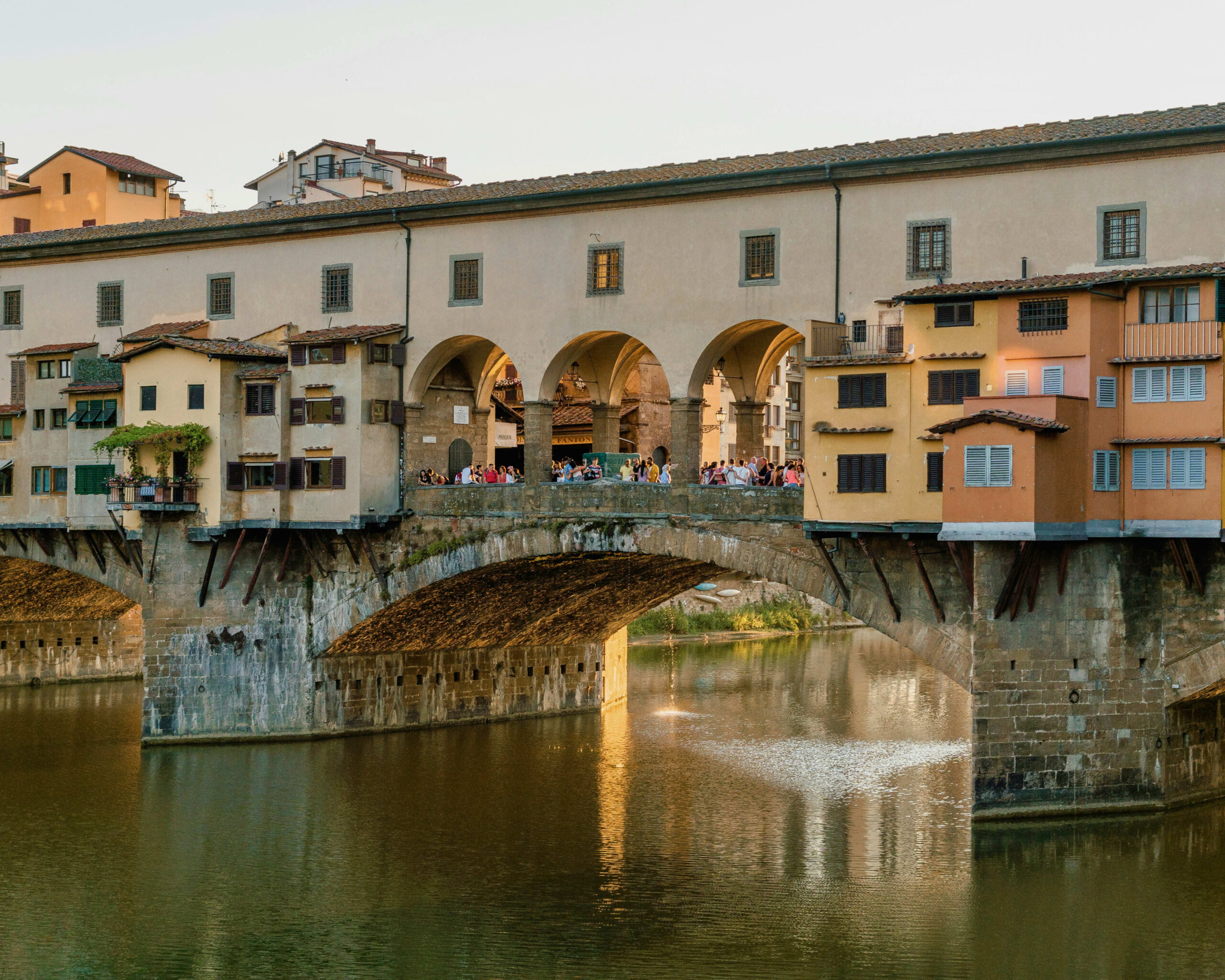 historic stone bridge over a river with multicolored homes on top of it during day